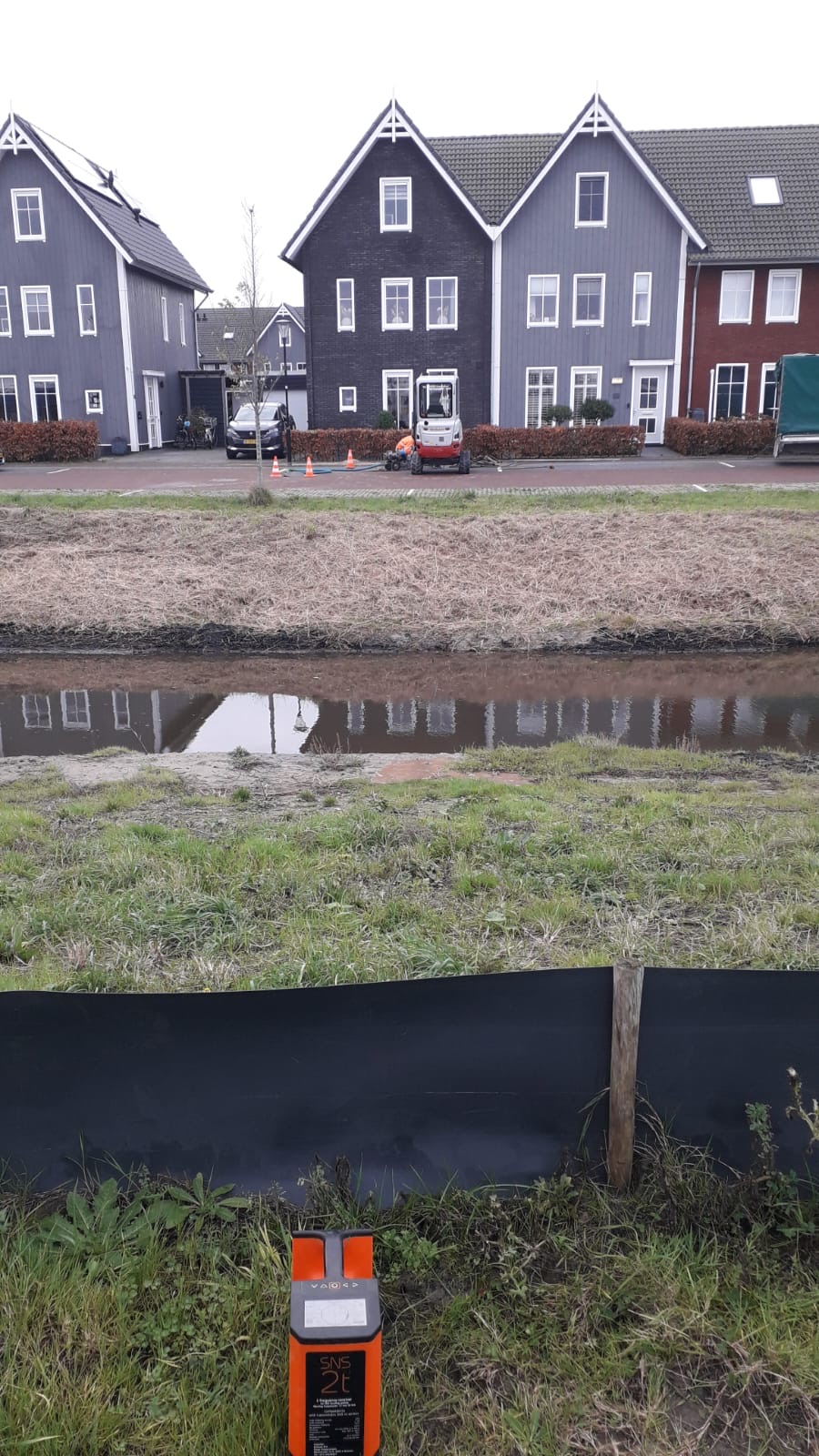 Werk bij een watergang en woningen